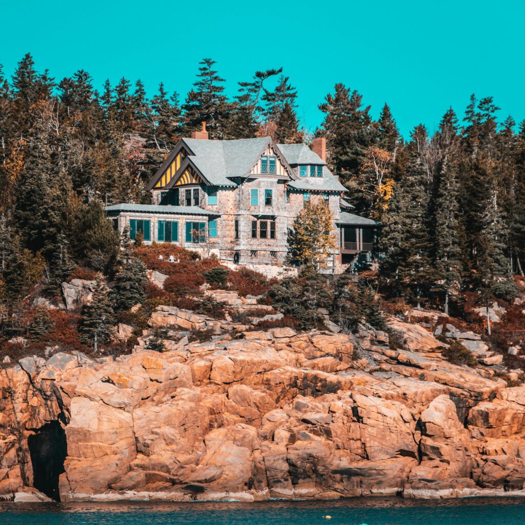 Picturesque house nestled in forested cliffs by the water, offering a serene natural backdrop.