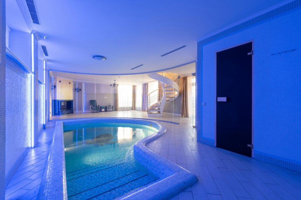 pexels photo 6957108 6957108 Swimming pool with clear water placed in spacious room at wall with blue illumination and staircase in contemporary luxury house
